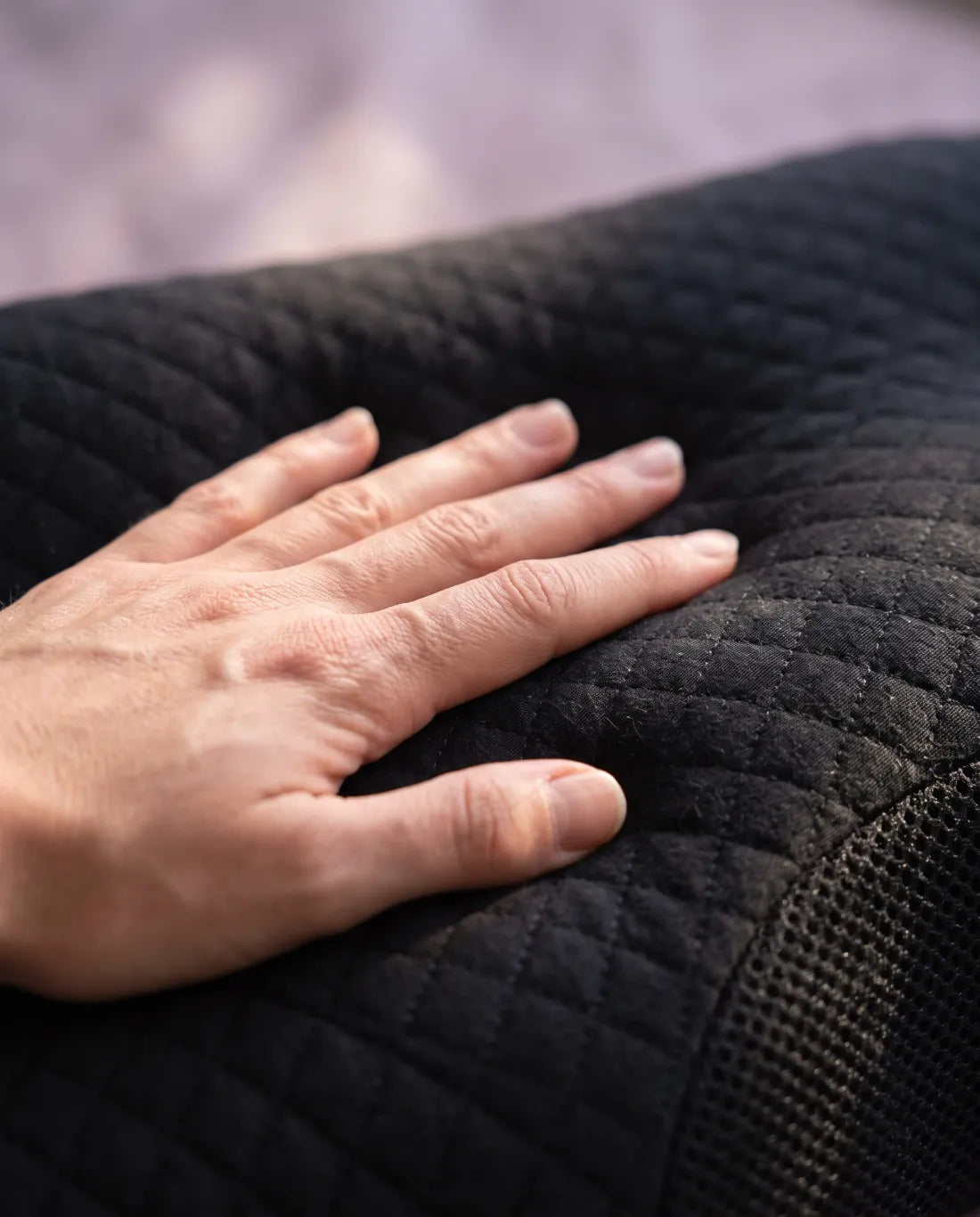 Main appuyant sur le tissu matelassé noir de l'oreiller
